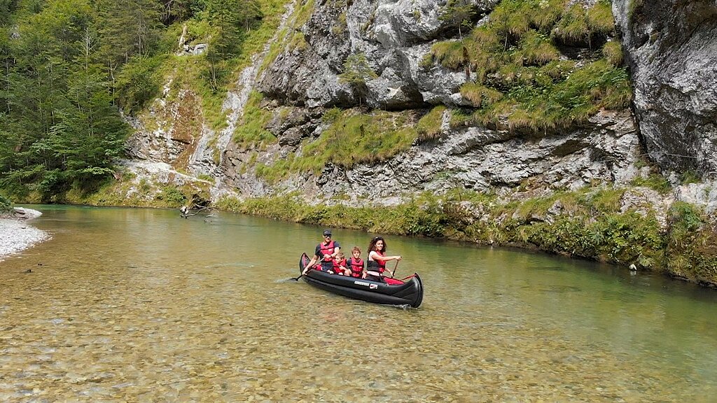 Paar mit zwei Kindern paddelt mit Luftkanadier am Fluss