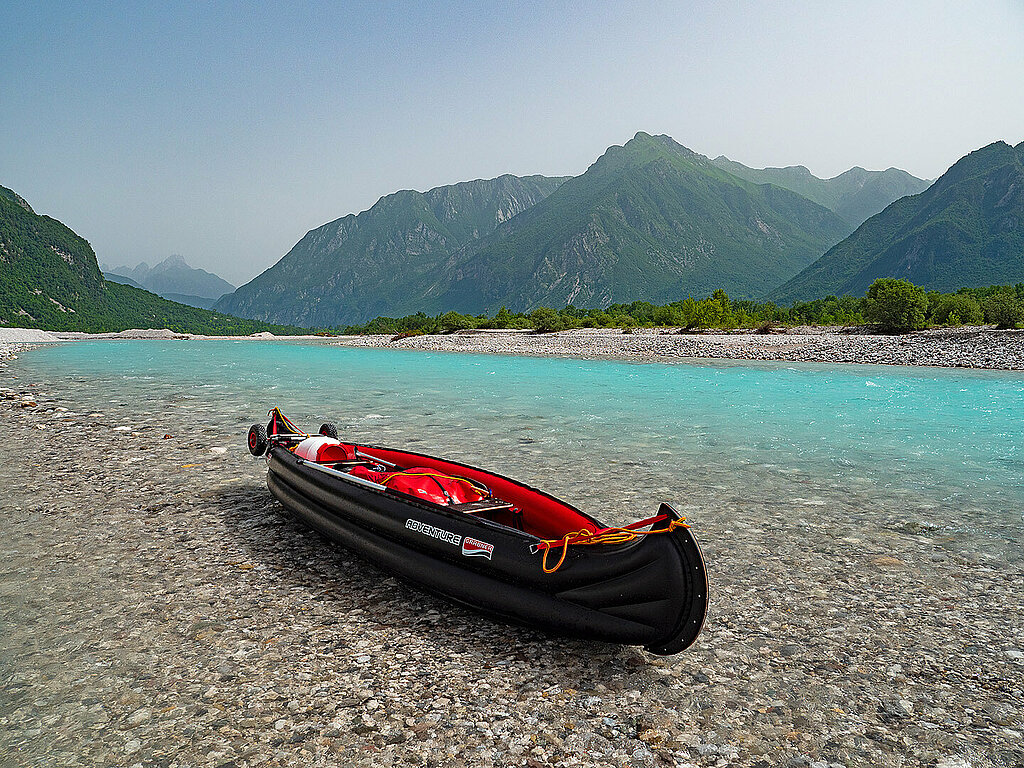 ein vollbepacktes aufblasbares Kanu auf türkisem Fluss