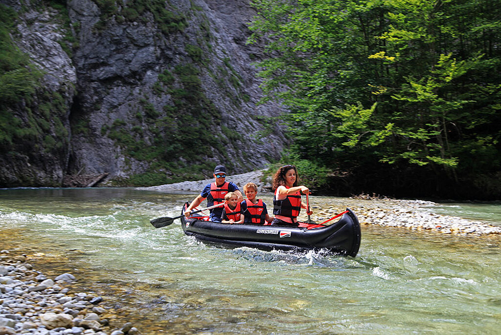 Familie paddelt mit aufblasbarem Kanu auf einem Fluss