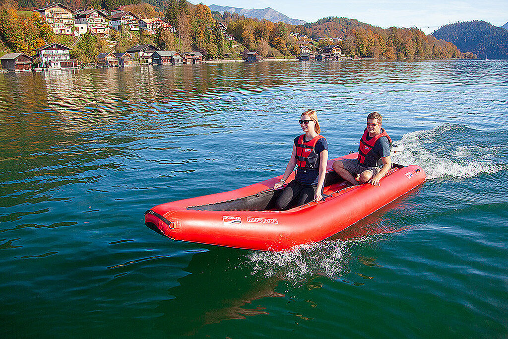 Pärchen fährt mit seinem Motor-Schlauchboot auf dem See 